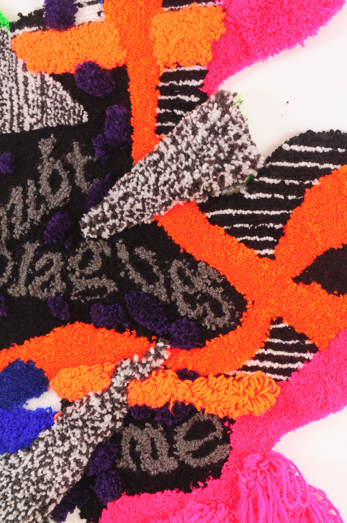 Fabric pieces glued together in abstract shapes in vibrant pink, blue, orange, green, black and gray with text